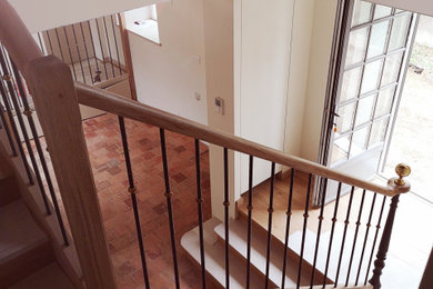 Aménagement d'un grand escalier classique en L avec des marches en bois, des contremarches en bois, un garde-corps en métal et palier.