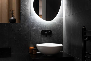 Photo of a medium sized modern bathroom in London with black tiles, black worktops and a single sink.