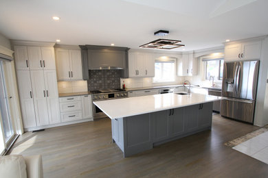 Eat-in kitchen - large contemporary l-shaped laminate floor and gray floor eat-in kitchen idea in Toronto with an undermount sink, recessed-panel cabinets, white cabinets, quartz countertops, white backsplash, porcelain backsplash, stainless steel appliances, an island and white countertops
