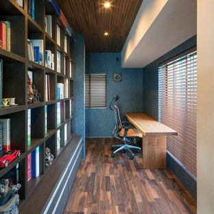 This is an example of a modern home office and library in Kobe with blue walls, dark hardwood flooring, a built-in desk and brown floors.