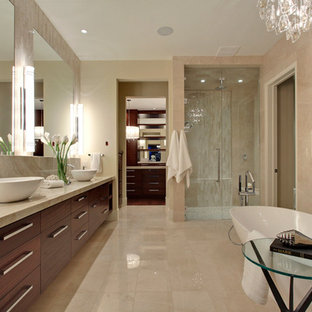 Esempio di una grande stanza da bagno padronale moderna con lavabo a bacinella, ante lisce, ante in legno scuro, top in granito, vasca freestanding, doccia a filo pavimento, WC monopezzo, piastrelle beige, piastrelle in pietra, pareti beige e pavimento con piastrelle in ceramica