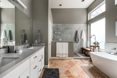 Photo of a mid-sized modern master bathroom in Phoenix with beaded inset cabinets, white cabinets, a freestanding tub, an open shower, a one-piece toilet, gray tile, cement tile, beige walls, ceramic floors, an integrated sink, marble benchtops, multi-coloured floor, an open shower and grey benchtops.