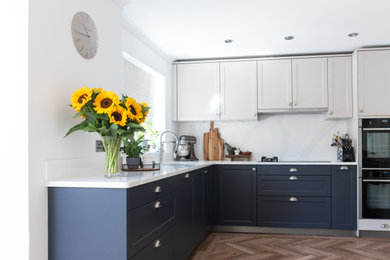 Photo of a mid-sized country eat-in kitchen in Hampshire with recessed-panel cabinets, quartzite benchtops, white splashback, no island and white benchtop.