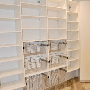 Cette image montre une grande arrière-cuisine rustique en U avec un évier encastré, un placard à porte plane, des portes de placard blanches, un plan de travail en quartz modifié, un électroménager en acier inoxydable, un sol en bois clair, un sol beige et un plan de travail noir.