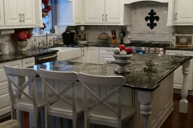 Open concept kitchen - mid-sized traditional u-shaped dark wood floor open concept kitchen idea in Philadelphia with a farmhouse sink, raised-panel cabinets, white cabinets, granite countertops, white backsplash, stone tile backsplash, stainless steel appliances and an island