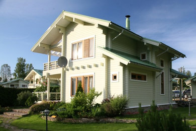На фото: двухэтажный, деревянный, желтый частный загородный дом среднего размера в стиле неоклассика (современная классика) с двускатной крышей и металлической крышей