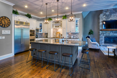 Photo of a large contemporary l-shaped eat-in kitchen in Nashville with raised-panel cabinets, granite benchtops, with island and black benchtop.