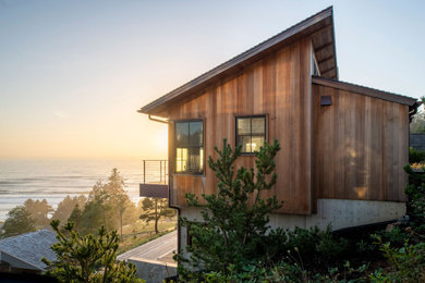 Inspiration for a coastal brown wood house exterior remodel in Portland with a black roof