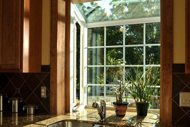 Example of a large farmhouse l-shaped medium tone wood floor eat-in kitchen design in New York with a double-bowl sink, recessed-panel cabinets, medium tone wood cabinets, granite countertops, porcelain backsplash and stainless steel appliances