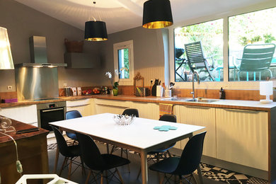 Réalisation d'une petite cuisine design en L et inox fermée avec un placard à porte affleurante, un plan de travail en bois, une crédence blanche, une crédence en carreau de ciment, un électroménager en acier inoxydable et îlot.