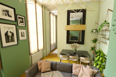 Modelo de sala de estar de tamaño medio con paredes verdes, suelo de madera clara y televisor colgado en la pared