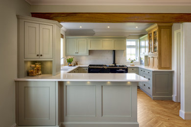 Photo of a large country u-shaped kitchen/diner in Sussex with a submerged sink, stone slab splashback, integrated appliances, a breakfast bar and feature lighting.