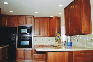 Eat-in kitchen - small traditional u-shaped travertine floor eat-in kitchen idea in Orange County with an undermount sink, raised-panel cabinets, medium tone wood cabinets, beige backsplash, black appliances, no island, granite countertops and stone tile backsplash