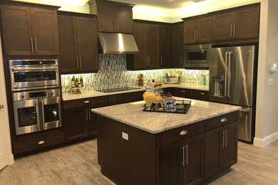 Exempel på ett mellanstort modernt beige beige kök, med skåp i shakerstil, skåp i mörkt trä, rostfria vitvaror, en köksö, granitbänkskiva, flerfärgad stänkskydd, stänkskydd i stickkakel, laminatgolv och beiget golv