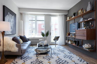 Example of a mid-sized mid-century modern enclosed medium tone wood floor family room design in New York with gray walls, no fireplace and a wall-mounted tv