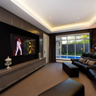 Cette image montre une salle de cinéma traditionnelle fermée avec un mur marron, un téléviseur fixé au mur et un sol marron.