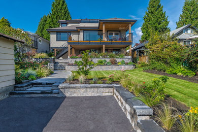 Inspiration for a large transitional backyard full sun formal garden for spring in Vancouver with a retaining wall and concrete pavers.