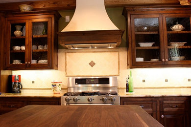 Inspiration for a large craftsman l-shaped beige floor and slate floor eat-in kitchen remodel in Houston with a double-bowl sink, raised-panel cabinets, medium tone wood cabinets, granite countertops, beige backsplash, stone tile backsplash, stainless steel appliances and an island