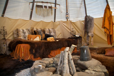 Example of a mid-sized mountain style guest bedroom design in Other with beige walls and a stone fireplace