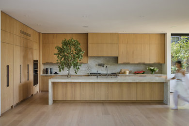 Inspiration for a large modern l-shaped light wood floor and beige floor open concept kitchen remodel in Los Angeles with an undermount sink, flat-panel cabinets, light wood cabinets, quartzite countertops, beige backsplash, stone slab backsplash, black appliances, an island and beige countertops