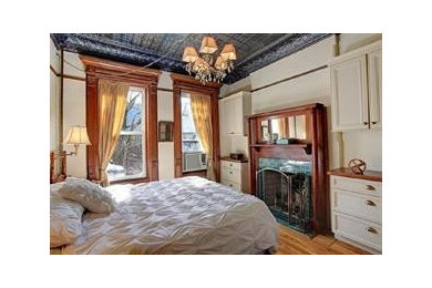 Mid-sized eclectic master medium tone wood floor bedroom photo in New York with a standard fireplace