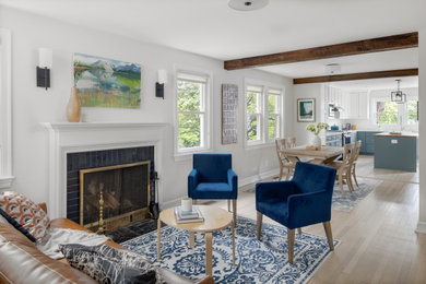 Mid-sized transitional open concept light wood floor and exposed beam living room photo in DC Metro with white walls, a standard fireplace, a brick fireplace and no tv