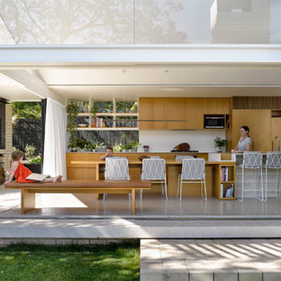 Esempio di una cucina ad ambiente unico design con ante lisce, ante in legno chiaro, paraspruzzi bianco e pavimento in cemento