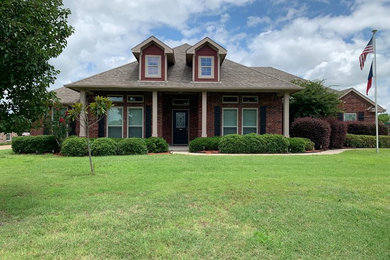 Mid-sized brown two-story brick house exterior photo in Dallas with a hip roof and a shingle roof