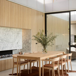 Inspiration for a contemporary dining room in Melbourne with beige walls, a ribbon fireplace and grey floor.