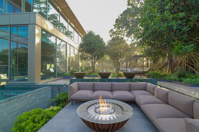 Patio - large contemporary side yard stone patio idea in Hertfordshire