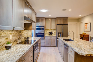 Mid-sized transitional light wood floor and brown floor kitchen photo in San Francisco with an undermount sink, recessed-panel cabinets, brown cabinets, beige backsplash, stainless steel appliances, an island and beige countertops