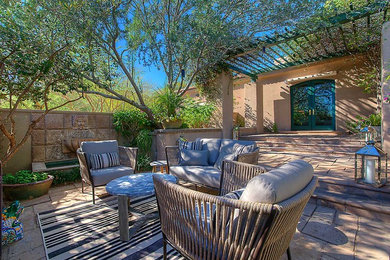Inspiration for a mid-sized backyard stone patio fountain remodel in Phoenix with a pergola