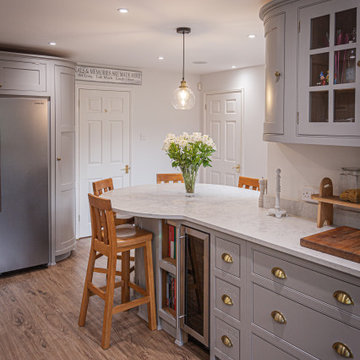 Light grey, traditional kitchen with glazed wall cabinets, round breakfast bar