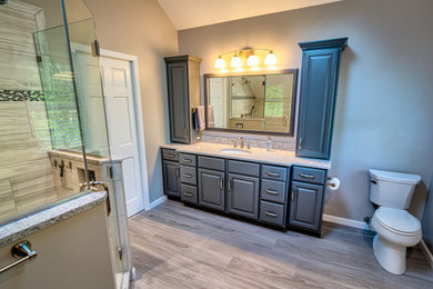 Example of a large classic master gray tile and porcelain tile porcelain tile, gray floor, double-sink and vaulted ceiling bathroom design in Philadelphia with raised-panel cabinets, gray cabinets, a two-piece toilet, gray walls, an undermount sink, quartz countertops, a hinged shower door, white countertops and a built-in vanity