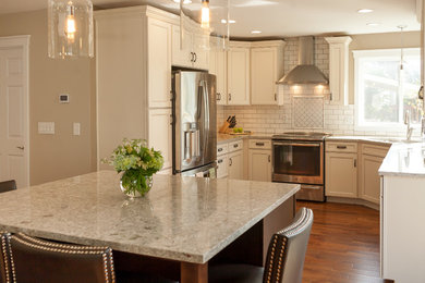 Eat-in kitchen - mid-sized traditional u-shaped dark wood floor eat-in kitchen idea in Seattle with an undermount sink, shaker cabinets, beige cabinets, granite countertops, white backsplash, subway tile backsplash, stainless steel appliances and an island