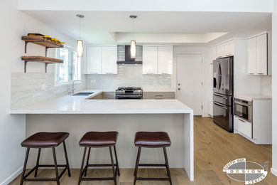 Kitchen - contemporary l-shaped medium tone wood floor kitchen idea in Los Angeles with an undermount sink, flat-panel cabinets, white cabinets, quartz countertops, white backsplash, subway tile backsplash and black appliances
