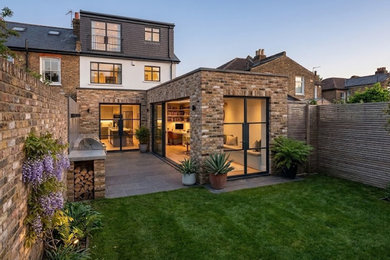 Inspiration for a multi-coloured brick and rear house exterior in Essex with three floors, a flat roof and a black roof.