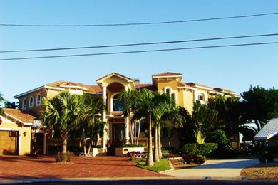Large tuscan yellow two-story concrete exterior home photo in Tampa with a hip roof