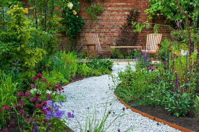 Imagen de jardín contemporáneo de tamaño medio en patio trasero con jardín francés, parterre de flores, exposición total al sol y piedra decorativa