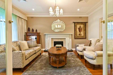 Mid-sized traditional formal enclosed living room in Sydney with medium hardwood floors, a standard fireplace, no tv and a stone fireplace surround.