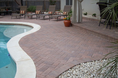 Example of a large island style backyard brick patio design in Austin with a roof extension
