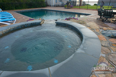 Large elegant backyard brick and custom-shaped hot tub photo in Providence