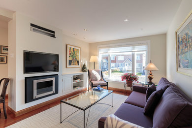Photo of a mid-sized contemporary open concept living room in Montreal with white walls, medium hardwood floors, a hanging fireplace, a plaster fireplace surround, a wall-mounted tv and brown floor.