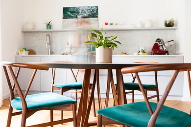 Immagine di una cucina contemporanea di medie dimensioni con lavello sottopiano, ante grigie, top in marmo, paraspruzzi bianco, paraspruzzi in marmo, elettrodomestici neri, pavimento in legno verniciato e top bianco