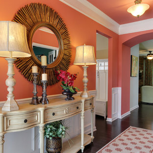 Inspiration for a mid-sized eclectic entry hall in Raleigh with orange walls, dark hardwood floors and brown floor.