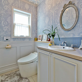 他の地域のトラディショナルスタイルのおしゃれなトイレ・洗面所 (落し込みパネル扉のキャビネット、白いキャビネット、青いタイル、青い壁、大理石の床、オーバーカウンターシンク、ベージュの床) の写真