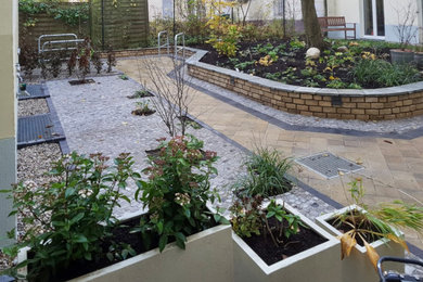 Diseño de jardín ecléctico de tamaño medio en otoño en patio trasero con macetero elevado, exposición reducida al sol y adoquines de piedra natural