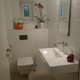 Cette photo montre un petit WC et toilettes tendance avec un WC séparé, un carrelage blanc, un carrelage métro, un mur blanc, un lavabo suspendu, un sol beige, un placard à porte plane, des portes de placard bleues, un sol en carrelage de céramique, un plan de toilette en acier inoxydable et un plan de toilette blanc.
