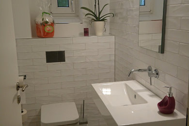 Kleine Moderne Gästetoilette mit Wandtoilette mit Spülkasten, weißen Fliesen, Metrofliesen, weißer Wandfarbe, Wandwaschbecken, beigem Boden, flächenbündigen Schrankfronten, blauen Schränken, Keramikboden, Edelstahl-Waschbecken/Waschtisch und weißer Waschtischplatte in Berlin