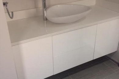 Example of a mid-sized transitional 3/4 porcelain tile and gray floor bathroom design in New York with flat-panel cabinets, white cabinets, white walls, a vessel sink and quartzite countertops